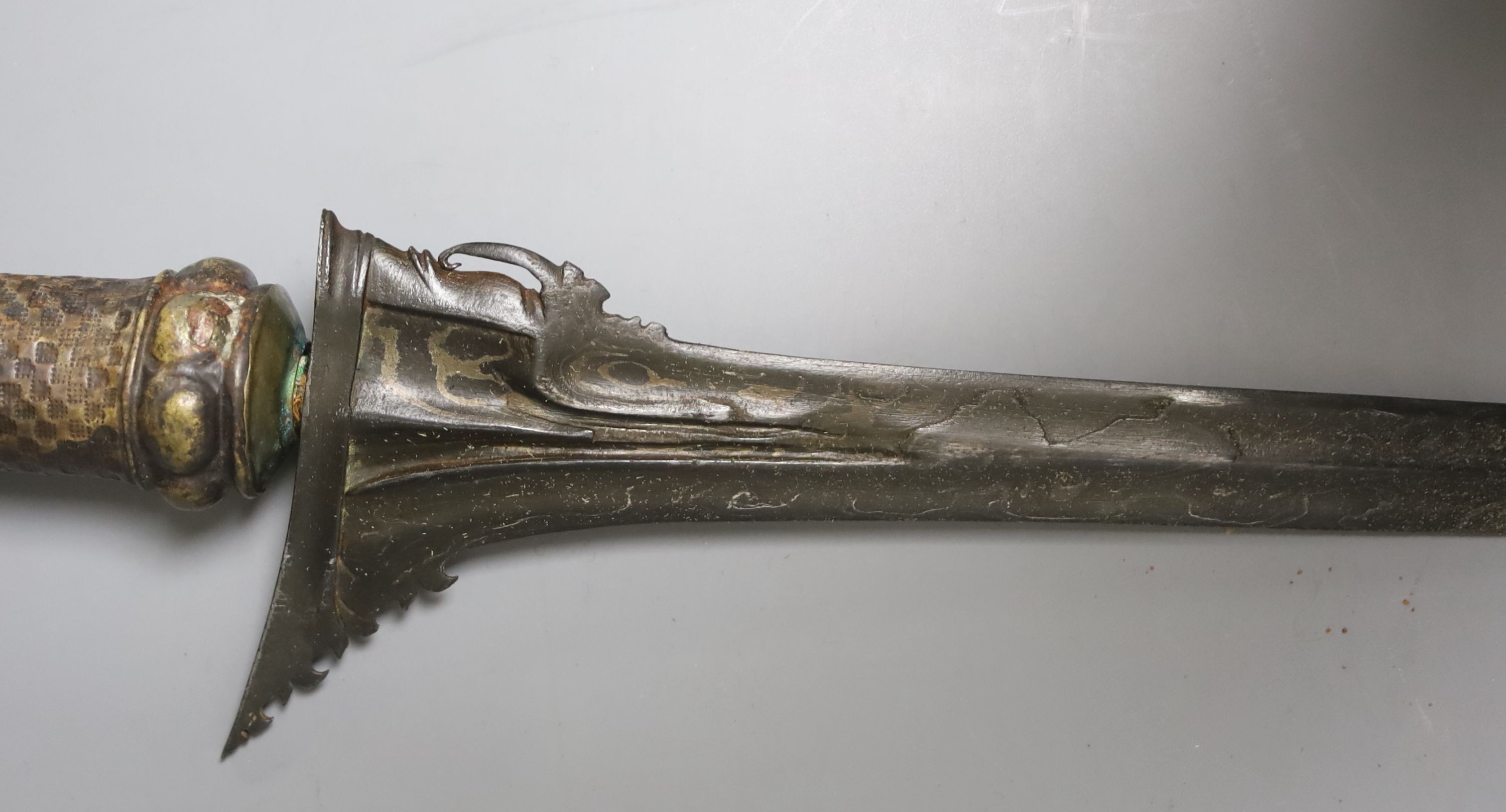 An Indonesian dagger kris, 19th century, earlier black and silver-coloured watered blade, brass hilt, wooden scabbard, blade 33cms